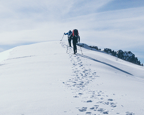 Dos personas caminando por la montaña nevada